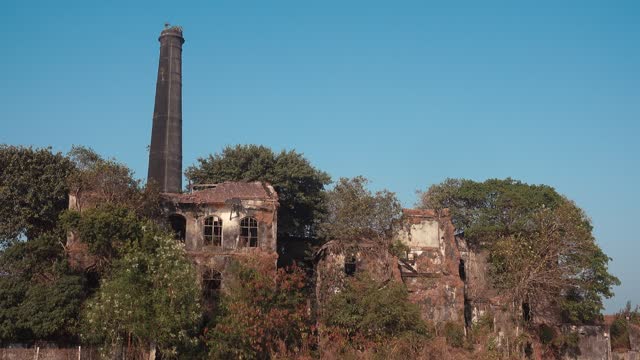 Old, damaged, and abandoned building with a tall brick chimney