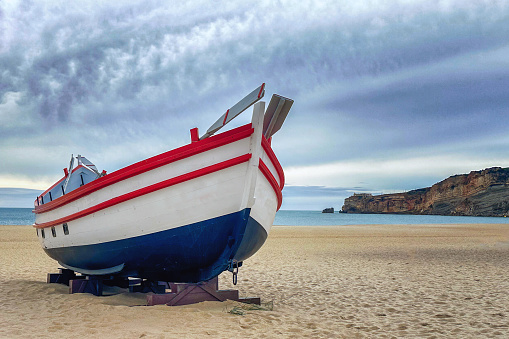 Boats in Nazare, Portugal at sunset on a cloudy day