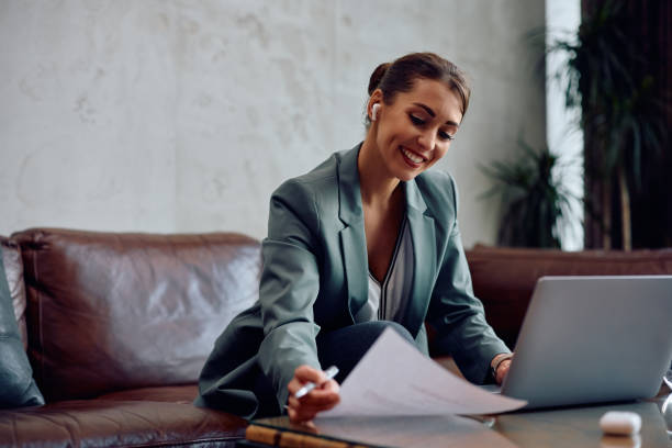 istock Happy businesswoman analyzing reports during conference call in hotel lobby. 2057971975