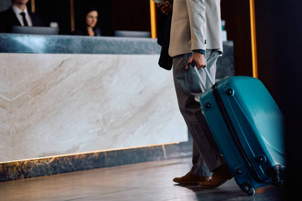 istock Unrecognizable black man with suitcase checking in at the hotel. 2057973612