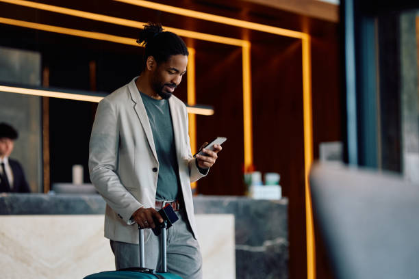 Happy black man using cell phone in a hotel lobby.