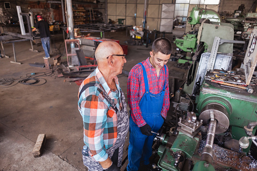 A grandfather and grandson duo collaborate on a metalworking project.