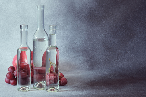 Still Life of Grapes Seen Through Water in Clear Glass Bottles