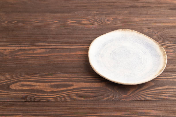 Empty blue and white ceramic plate on brown wooden background. Side view, copy space.