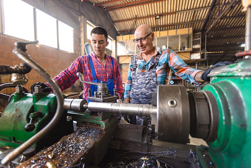 A grandfather demonstrating metalworking skills to his eager young grandson.