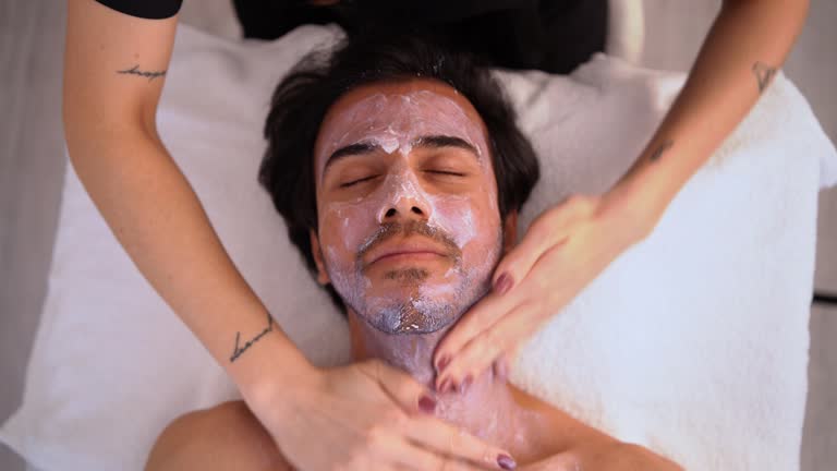 Dermatologist spreading cream in the face of a man