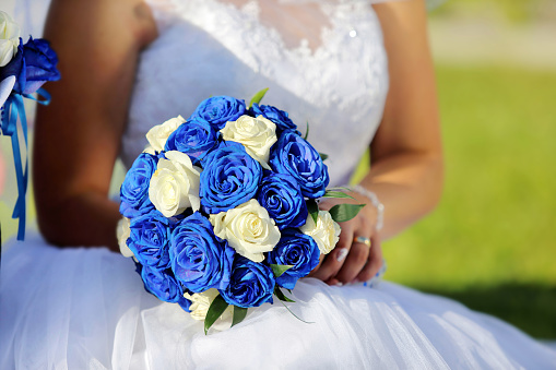 Blue wedding bouquet of roses in the hands of bride and empty space for text