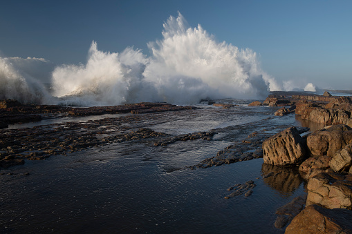 Breaking wave in rocky coastline. Splashing droplets. Barreiros, A Mariña area, Lugo province, Galicia, Spain.