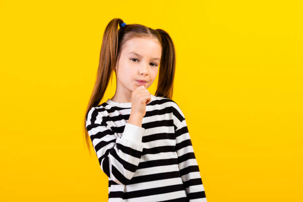 istock Photo of uncertain funny little child dressed striped pullover arm chin empty space isolated yellow color background 2058083654