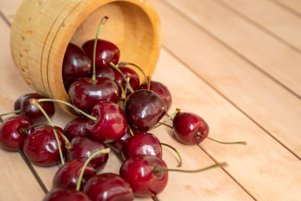 sweet cherries scattered from bowl on wooden table surface