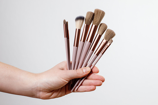 makeup brushes in hand on a gray plain background