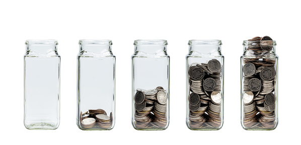 Growing savings concept. Glass jar of coins isolated on white background. Jars with different level of coins with clipping path