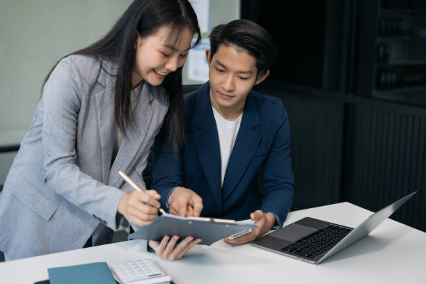 istock Business, technology and office concept - two businessmen with laptop, tablet pc computer and papers having discussion in modern office. 2058135951