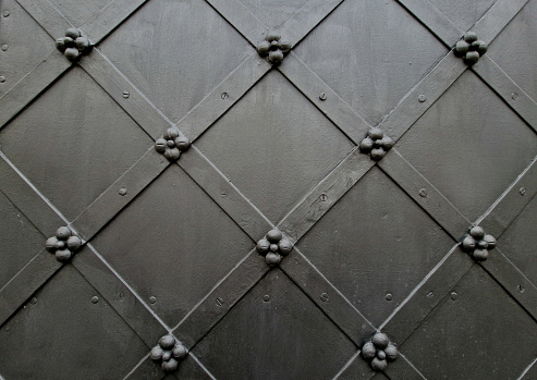 Wrought iron door with grid pattern. medieval style with rivets and bands of steel. beautiful and stylish fortress gothic with flowers shape. construcion