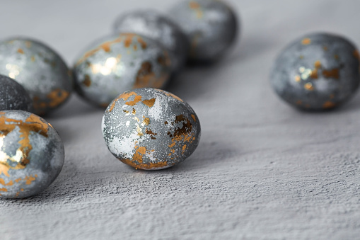 Stylish grey Easter eggs made of marble and concrete with a golden potala on a grey background. Coloring eggs with natural dye karkade tea. The concept of a happy Easter.