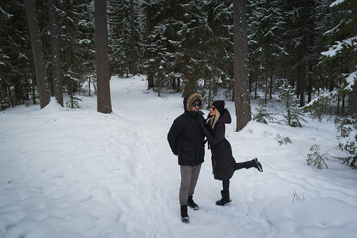 A young couple in sunglasses walks in the forest on a winter day. High quality photo