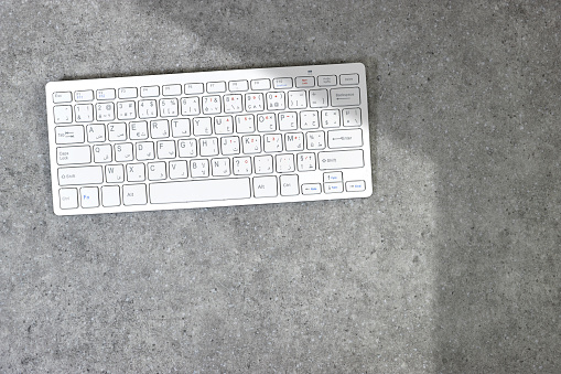 Modern aluminum computer keyboard isolated on grunge gray background