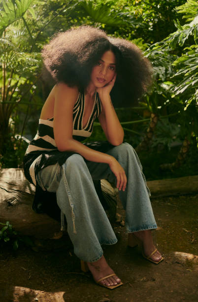 A confident woman with a afro hairstyle sitting elegantly in a lush garden