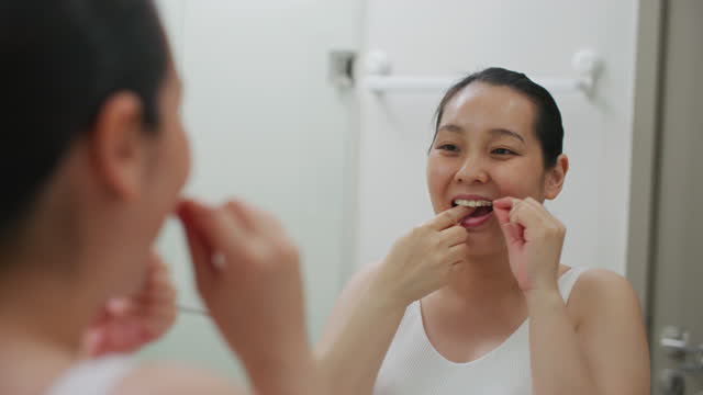 Woman flossing her teeth while removing leftover food from the interdental space