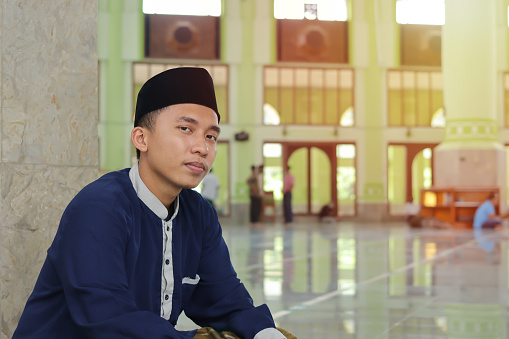 Portrait of religious Asian man in muslim shirt sitting in mosque