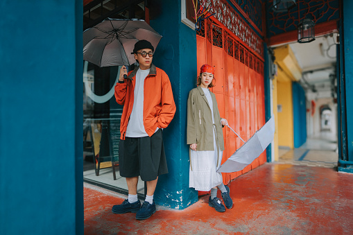 Portrait Asian Chinese Couple holding umbrella standing in corridor of Penang old town shoplot