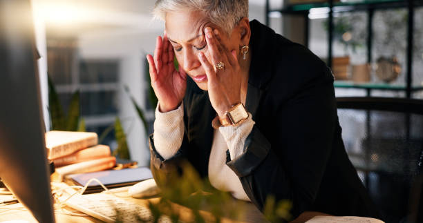 istock CEO, stress and headache by computer in office with tension for burnout, frustrated and overworked at night. Woman, boss and anxiety with hand on temples for pressure, migraine and pain at workplace 2058181370