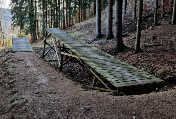 jumps and the construction of benches for jumps and terrains of dirt inclined paths in the former bobsleigh track, now used as cycle tracks for enduro cyclists. long flights over the abyss, ruin jumps and the construction of benches for jumps and terrains of dirt inclined paths in the former bobsleigh track, now used as cycle tracks for enduro cyclists. long flights over the abyss, downhill, activity, mtb, tilted, curve, fast, construction frame jump board stock pictures, royalty-free photos & images