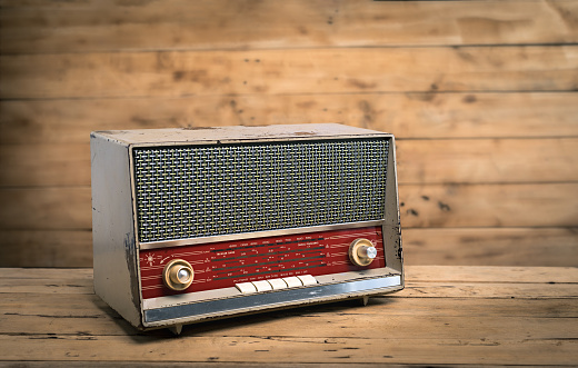 Old retro radio on wood table with old wooden wall, background