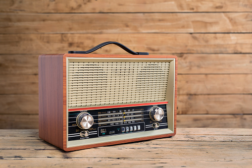 Old retro radio on wood table with wooden wall, background