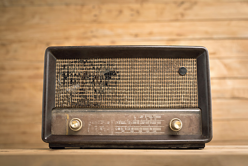 Front view of old retro radio on wood table with wooden wall, background