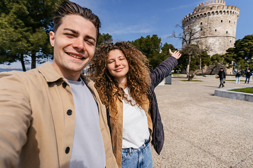 Young couple taking selfies using smart phone in the park in Thessaloniki, Greece.