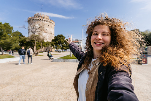 Young woman taking selfies using smart phone in the park in Thessaloniki, Greece.