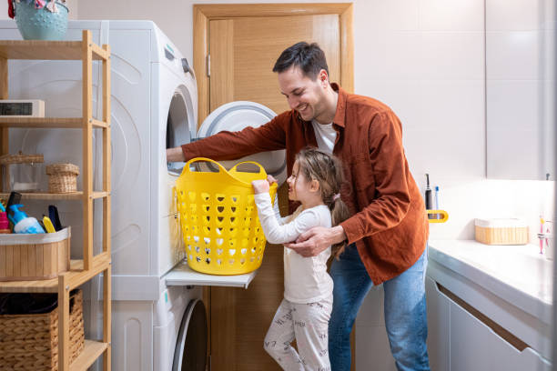 Caucasian father and daughter, taking out the clothes from the dryer stock photo
