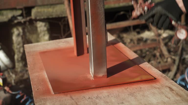 Craftsman paints a metal structure using a spray gun. Worker applies paint with paint sprayer and compressor. Slo-mo