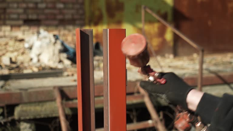 Craftsman paints a metal structure using a spray gun. Worker applies paint with paint sprayer and compressor. Slo-mo