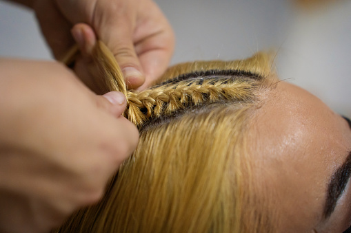 Hairstylist making braids at hair saloon