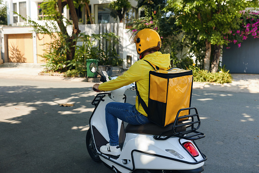 Courier riding motorbike, delivering food to customers