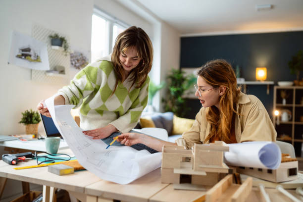 Two female architecture students making architectural model of a modern house