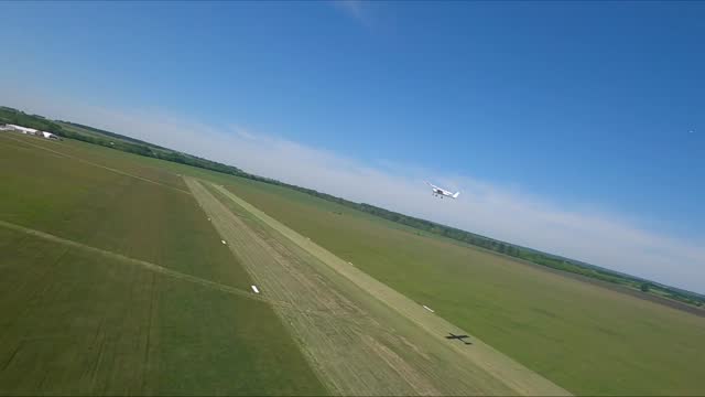Small airplane with propeller engines flying in a clear blue sky. Aerial view to lightweight plane flight above rural airport. Travel at ultralight sport aircraft. Aviation concept. Drone shot