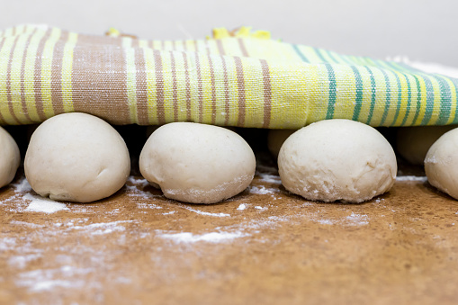 Preparing food. Uncooked dough for pizza and bread on a table covered with a towel.