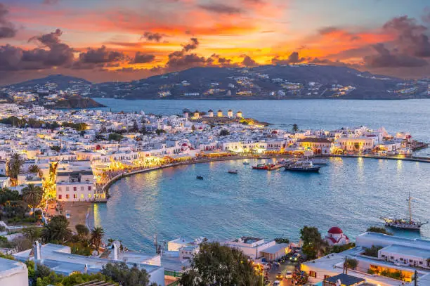 Embrace the warm hues of sunset in Mykonos Town Chora, where the Aegean Sea's azure waters reflect the vibrant life of this iconic Greek island.