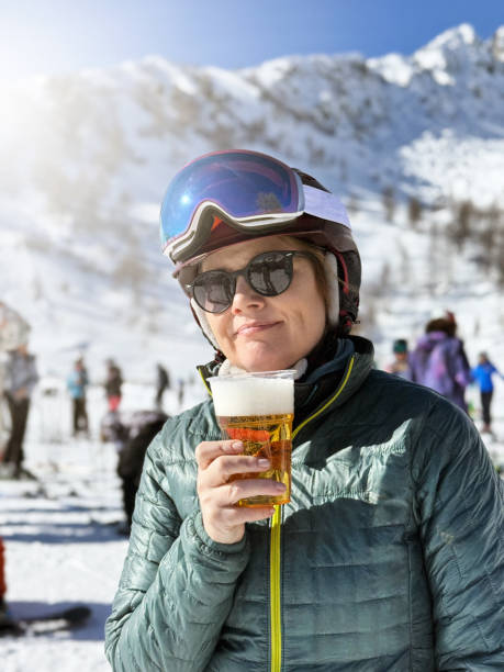 retrato de una hermosa mujer madura que se toma un descanso del esquí tomando un vaso de cerveza - beer ski apres ski snow fotografías e imágenes de stock