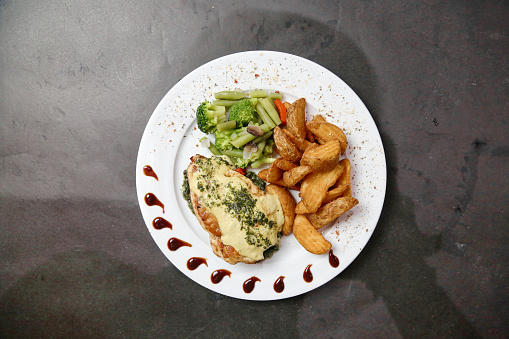 A white plate filled with a delicious combination of golden chicken, crispy fries, and vibrant broccoli.