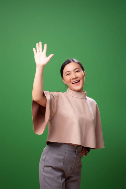 istock Asian woman smiling confidence making high five gestures, isolated on green background. 2058321046