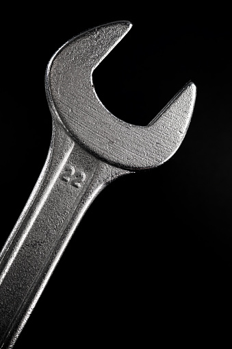 Close up of a metal wrench on a black background