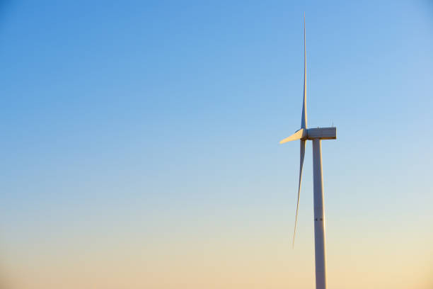 A white wind turbine showing some movement against a deep blue sky.
