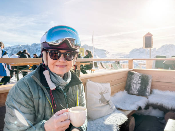 スキー場のカフェで温かいコーヒーを楽しむ幸せな成熟した女性スキーヤー - apres ski copy space happiness smiling ストックフォトと画像