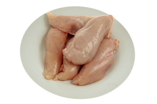 Plate of raw chicken fillets close-up on white background