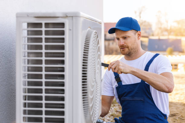 technician working on air conditioning or heat pump outdoor unit. HVAC service, maintenance and repair stock photo