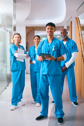 Portrait Of Smiling Multi Cultural Medical Team Wearing Scrubs In Modern Hospital